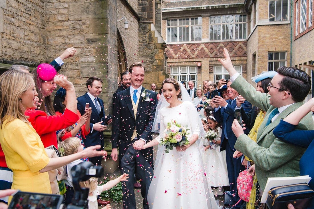 the married couple enjoying confetti outside church