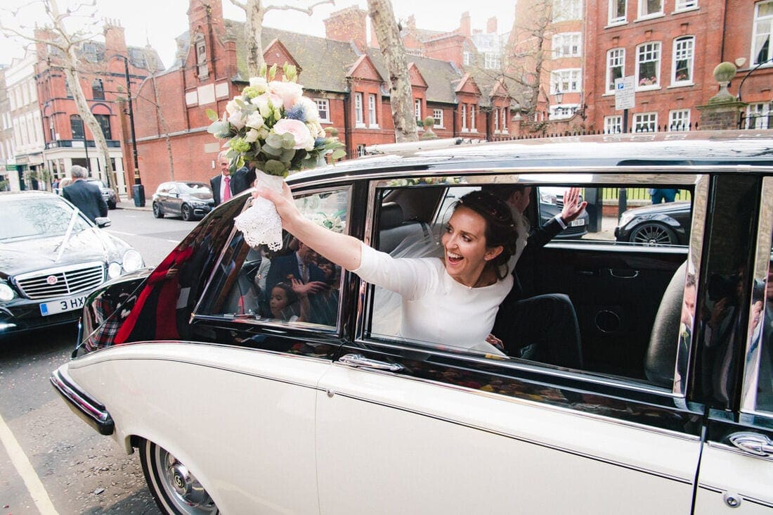 bride waving to the wedding guests