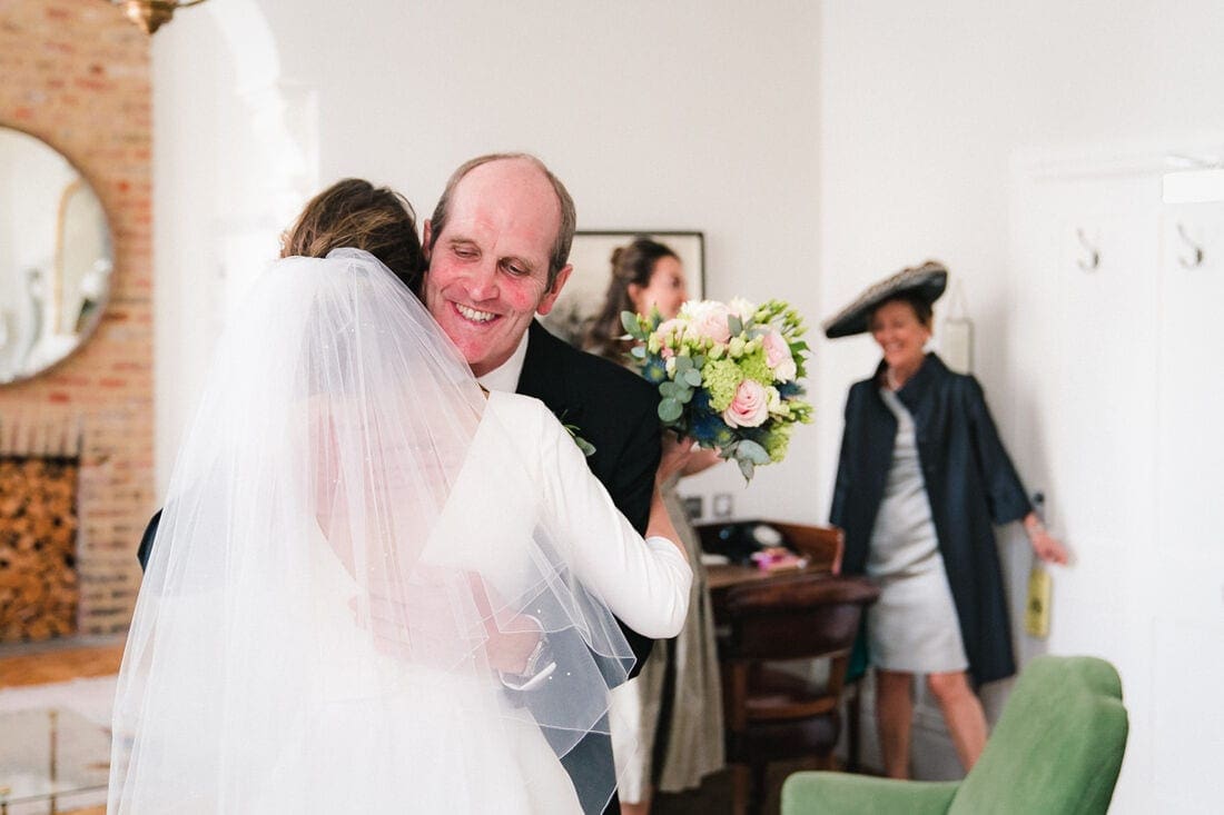 a hug between the bride and her dad before traveling to church